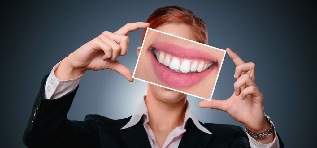 Woman holding a photo of beautiful white teeth