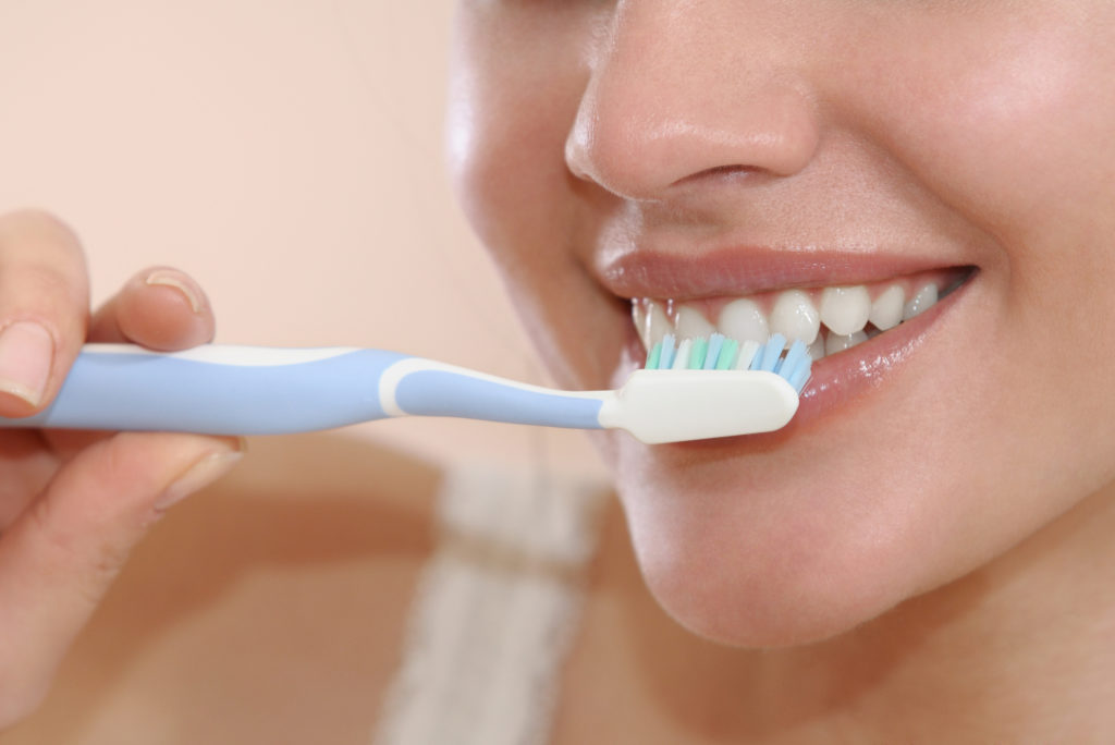 Smiling woman brushing her teeth