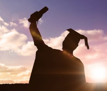 Silhouette of graduate against sun shining