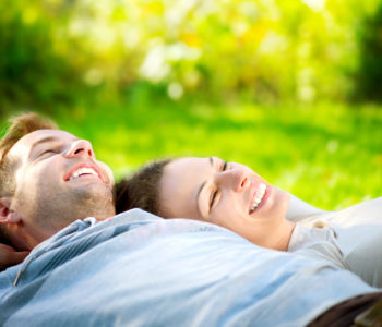 Park. Young Couple Lying on Grass Outdoor