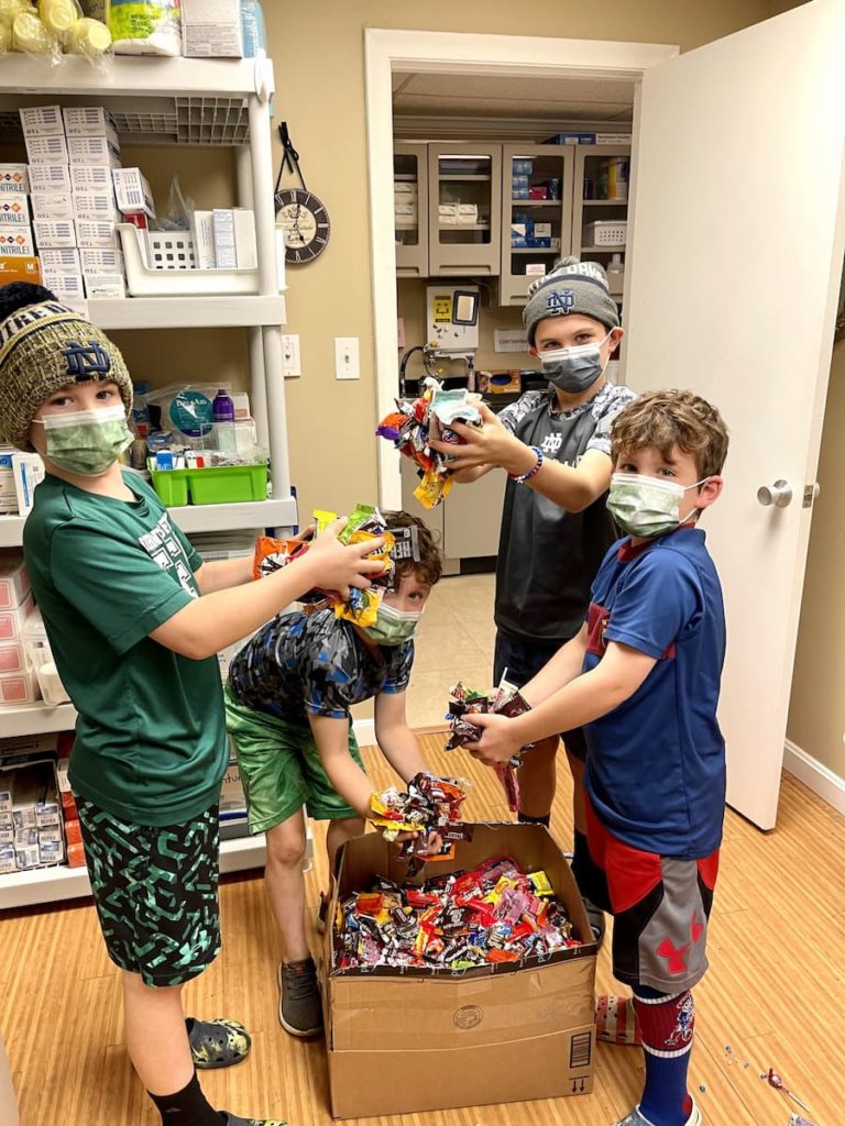 Kids standing over a box of candy, holding handfuls of candy.