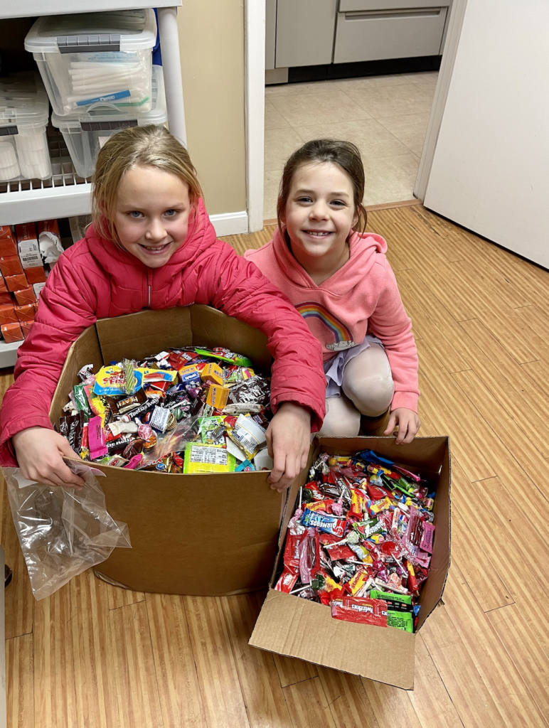 Kids beside candy Two children smiling at the camera while lording over a cardboard box stuffed with candy.