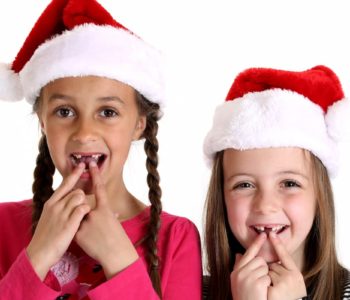 girls wearing santa hats missing their two front teeth